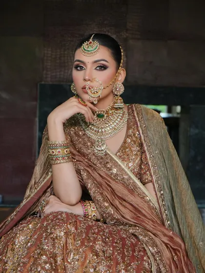 A close-up portrait highlighting the intricate jewelry and the delicate drape of the dupatta. The fabric is styled to frame the face and shoulders, adding to the overall regal feel of the look.