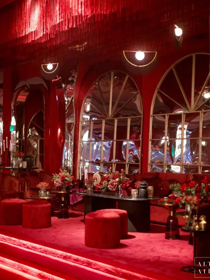 A lounge area at 'Le Rouge' with tiered seating, all upholstered in rich red velvet. The distorted mirrors and fringe ceiling installation added to the dramatic, immersive experience.