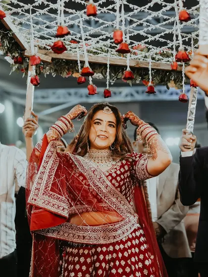 A happy bridal entry shot, with the bride dancing under a 'phoolon ki chadar' of red roses. Her joyful expression is infectious.