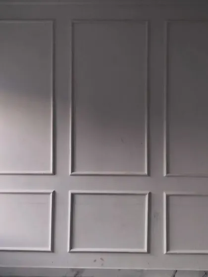 The wall panel molding before painting, showcasing the precision of the installation and the classic structure it adds to the room.