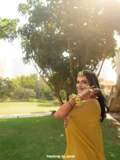 A beautiful outdoor shot of the Haldi bride. The sunlight highlights her glowing skin and the fresh, natural makeup look.