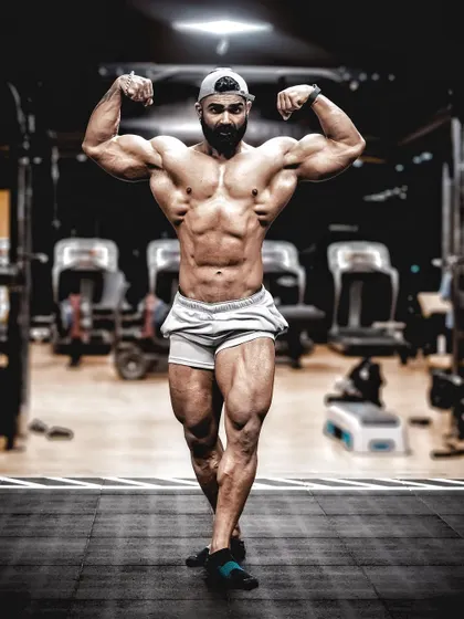 A full-body shot of the front double bicep pose, demonstrating how to present a complete, balanced physique from head to toe.