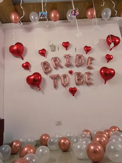 A full view of the room decorated for a bridal shower, with a 'Bride to be' wall backdrop and balloons on the ceiling and floor.