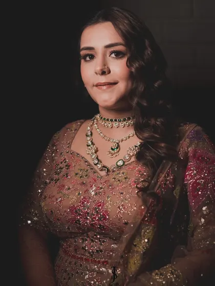 A portrait of the bride, showcasing her beautiful makeup and the intricate details of her layered necklaces, perfect for a glamorous Sangeet night.