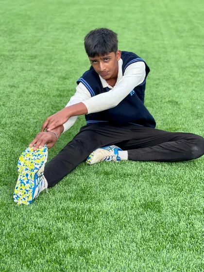 A young cricketer stretches his hamstring. We ensure our players understand the importance of a proper warm-up and cool-down.