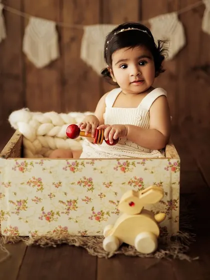 A curious little one exploring the studio during her sitter session. The floral box and wooden toys create a playful and engaging environment.