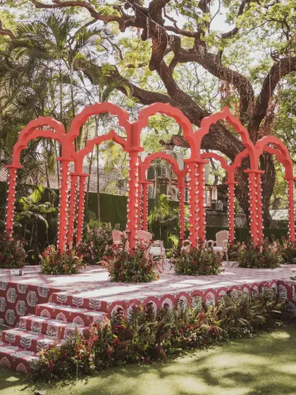 The vibrant red 'Gulal Bagh' mandap, inspired by Jaipuri architecture, stands out beautifully against the lush green backdrop.