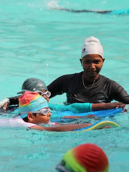 A coach guides multiple students on kickboards. This shows how we manage group lessons effectively, ensuring everyone gets the attention they need.