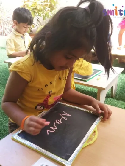 A girl carefully writes on a slate with chalk during our Vasant Panchami celebration. This traditional activity honors the goddess of knowledge, Saraswati, and connects children with timeless learning methods.