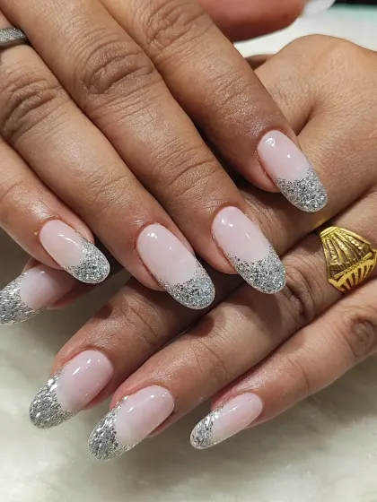 Glamour meets classic in this glittery French tip design. The long, oval nails have a sheer pink base and tips packed with sparkling silver glitter, perfect for any party or special occasion.