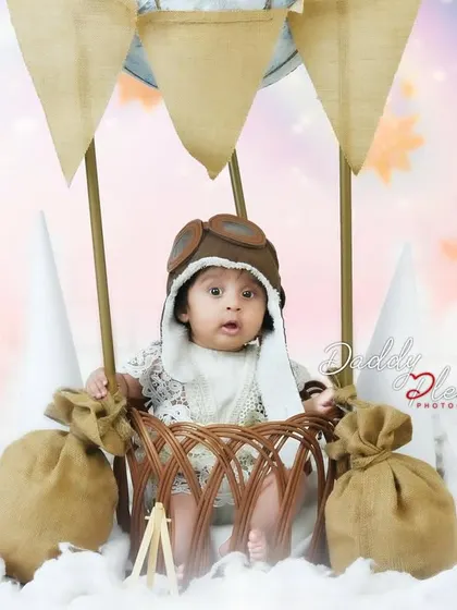 A closer shot of the baby in the hot air balloon setup, showing the details of the basket and the baby's cute pilot hat.