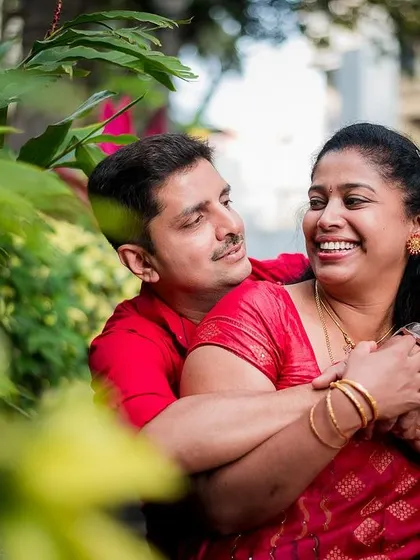 A candid and affectionate moment between a couple, framed by lush greenery. We specialize in capturing these natural, loving interactions.