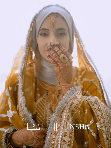 A stunning, ethereal portrait of the Kashmiri bride Insha, her face partially covered by her hand, drawing attention to her expressive eyes.