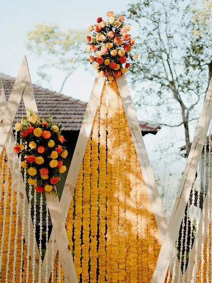 The bright and happy vibes of this Haldi are perfectly captured in this image. The marigold and tuberose blooms, combined with the modern backdrop, create a truly memorable setting.