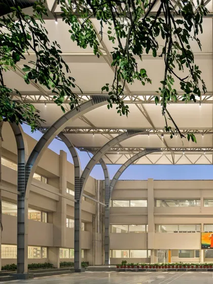 Framed by foliage, the canopy structure feels integrated with the natural elements of the campus, providing shelter while remaining open to the environment.