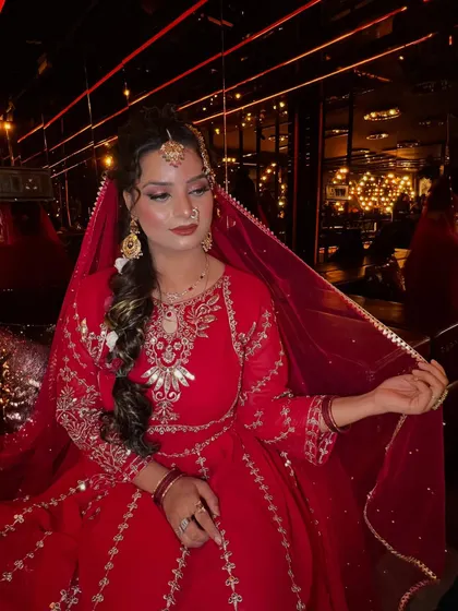 This image captures the bride's elegance, with her holding the sheer red dupatta. The focus is on the intricate embroidery of her outfit and the way the makeup complements the traditional aesthetic.