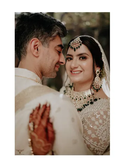 A sweet and classic pose. The bride looks warmly at the camera while being embraced by her groom, a timeless portrait that radiates happiness.