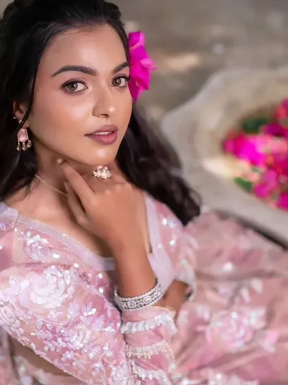 A model showcasing a glamorous look with a pink lehenga, perfect for a reception or sangeet. The makeup is subtle yet striking.