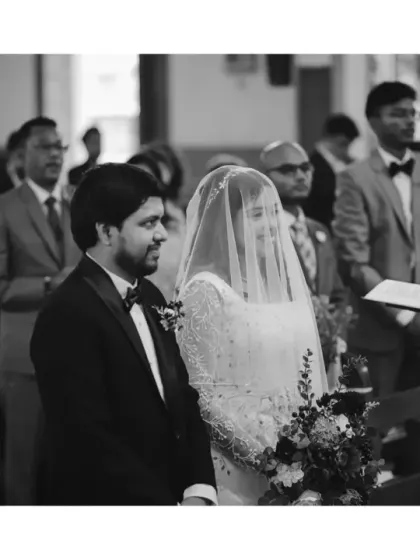 A solemn and beautiful black and white shot of the couple at the altar during their church wedding. The monochrome tones emphasize the reverence and emotion of the moment.