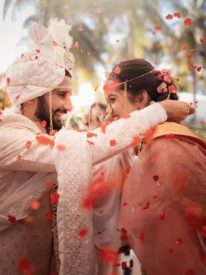 A shower of rose petals rains down as the couple exchanges garlands. This frame is bursting with color, movement, and the sheer joy of the Varmala ceremony.