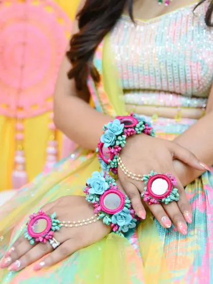 A close-up on the bride's hands, showing off her floral jewelry and nail art.