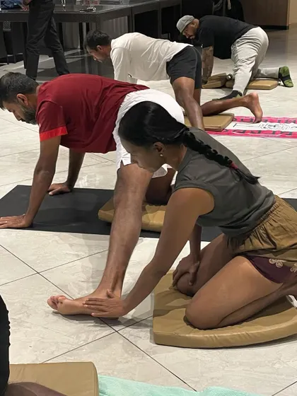 I am adjusting a player's foot alignment in a low lunge. The foundation of every pose is in the feet, and for athletes, proper foot mechanics are essential for preventing injuries.