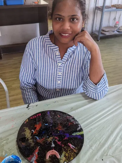 A participant with her finished galaxy-themed resin clock. The mix of dark blues, purples, and sparkling glitter creates a beautiful cosmic effect that's out of this world.