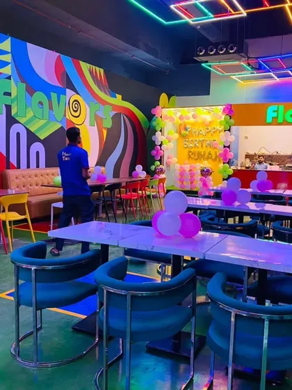 A wide shot of the cafe decorated for Ruhani's birthday, showing the colorful chairs and tables of the venue.