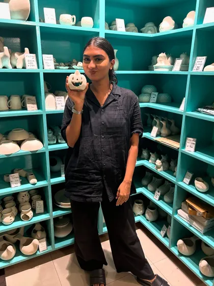 A guest proudly shows off the small, smiling pumpkin she's chosen to paint from our extensive collection of unpainted ceramics.