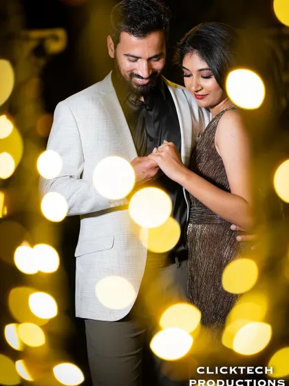 An intimate shot of a couple holding hands, framed by the beautiful bokeh of warm fairy lights, creating a romantic and artistic effect.