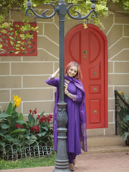 The model poses by a classic lamppost and a bright red door, a perfect setting for a vibrant and stylish fashion shot.
