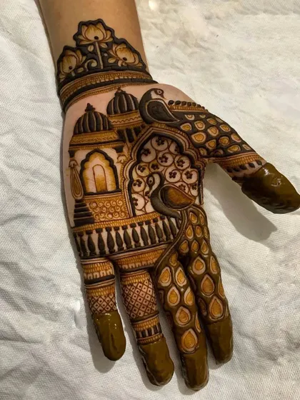 A creative take on the peacock motif, where the bird's feathers are integrated with the fingers. This design also features royal palace architecture on the palm.