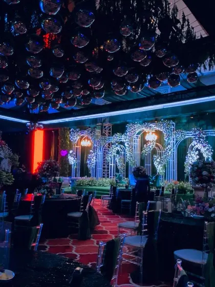 Time for the party. This sangeet night was all about high energy, with a ceiling full of disco balls, dramatic blue and red lighting, and elaborate floral arches, setting the stage for an unforgettable night of dancing.