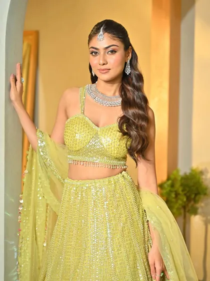 A full view of the Sangeet look. The simple, elegant hairstyle allows the bride's outfit and jewelry to shine.