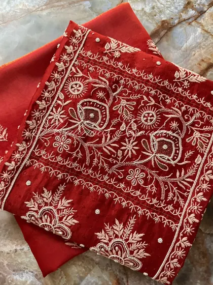 A folded view of the kurta, emphasizing the rich red color and the white threadwork.