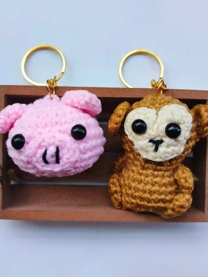 A clean product shot of the pig and monkey amigurumi keychains. They are the perfect size to hang on your keys or backpack without being too bulky.