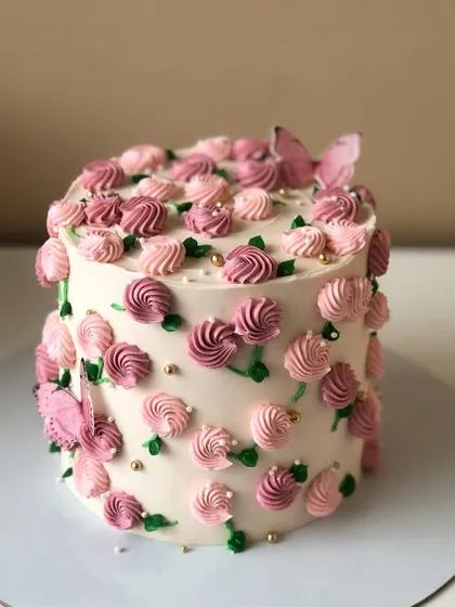 A pretty cake with pink-on-pink floral piping and delicate edible butterflies.