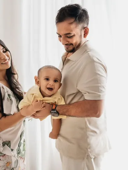 A lovely family of three, smiling together. This photo was taken during a first birthday session, showing how we can easily mix family portraits into milestone shoots.