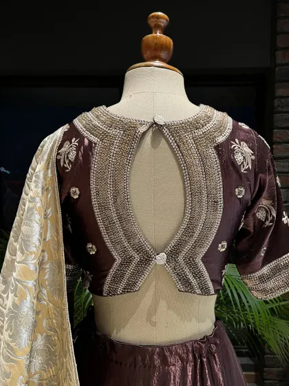 A close-up of the intricately embroidered blouse of the brown lehenga, showcasing the detailed craftsmanship that goes into every piece.