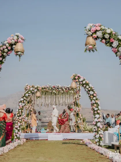 The stunning floral mandap with hanging bells, set against the hills of Karjat, providing a breathtaking backdrop for the wedding ceremony.