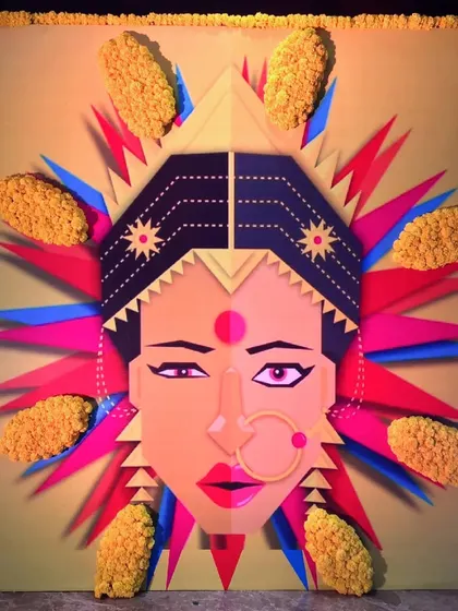 A close-up of a modern graphic art panel depicting a woman's face, with 3D floral accents made from yellow marigolds, blending art with decor.