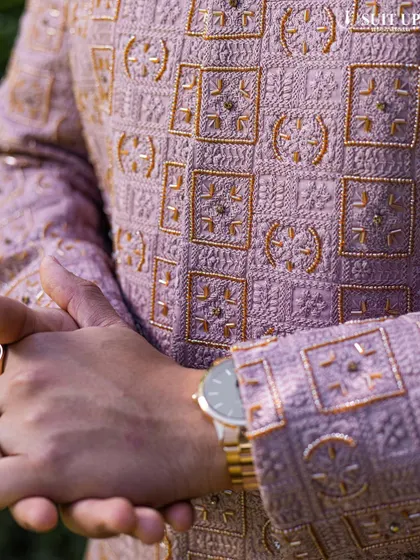 A close-up of a client's mauve sherwani, highlighting the intricate geometric embroidery in gold thread.