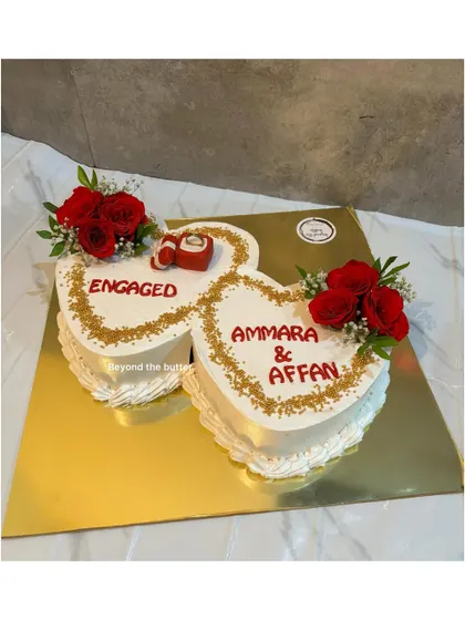 A double heart engagement cake to celebrate two hearts becoming one. This design is decorated with fresh red roses and a fondant ring box, symbolizing the couple's commitment.
