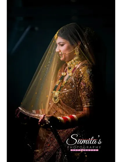 A beautifully lit portrait of the bride under her veil. The warm light creates a golden glow, emphasizing her traditional jewelry and serene expression.