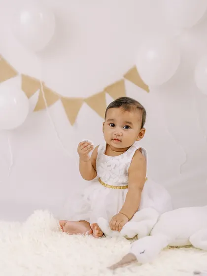 A simple and sweet portrait of a six-month-old girl in a white dress, ready for her milestone session.