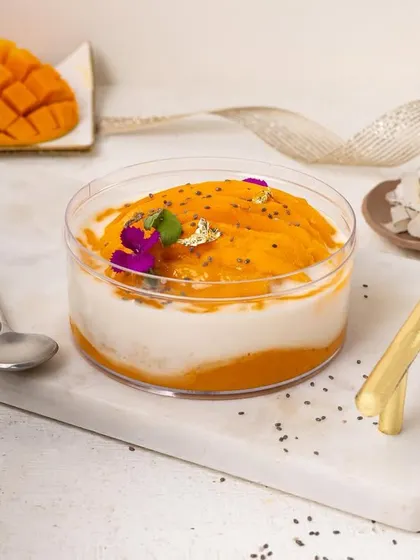 A bright and fresh mango and coconut tub dessert, styled on a clean white marble slab.