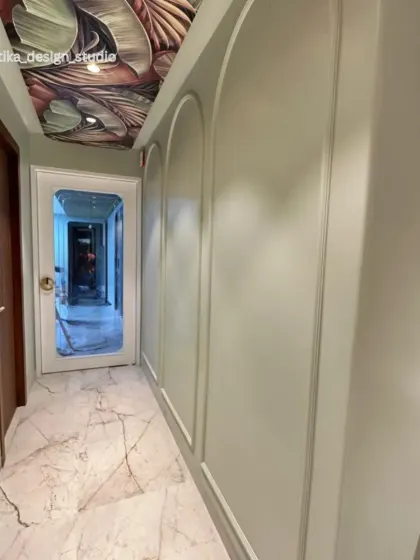 Looking down the hallway, this view shows how the combination of the statement ceiling, arched moldings, and clean marble floors creates a passage that feels both grand and modern.