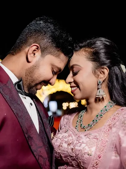 A happy, close-up portrait of the couple smiling, with beautiful bokeh from the reception lights.
