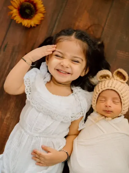 The pure joy on a big sister's face as she lies next to her new sibling. These are the real, unscripted moments that families will treasure.