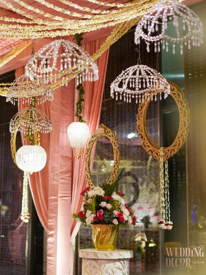 A detail of the ceiling decor, featuring crystal umbrellas, ornate golden mirrors, and hanging floral arrangements. This eclectic mix of elements creates a rich and festive atmosphere.
